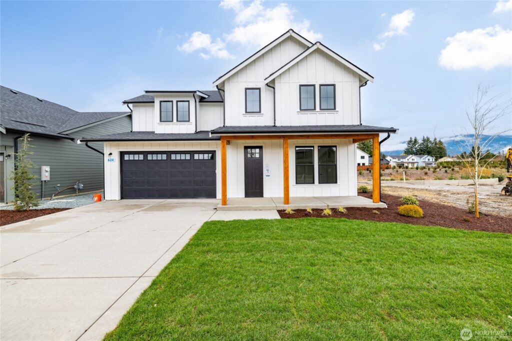 Modern two-story house exterior with garage, front porch, and landscaped yard